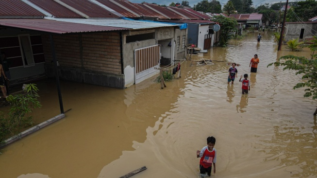 Foto udara warga melintasi deretan rumah terendam banjir di Perumahan Griya Aci Indah, Kelurahan Lepo-Lepo, Kendari, Sulawesi Tenggara, Senin (30/6/2025). [ANTARA FOTO/Andry Denisah/rwa]