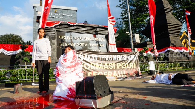 Massa dari Koalisi Masyarakat Sipil untuk Reformasi Kepolisian (Koalisi RFP) menggelar aksi teaterikal di depan Polda Metro Jaya, Jakarta, Selasa (1/7/2025). [Suara.com/Alfian Winanto]