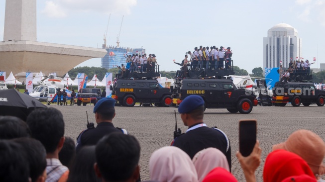 Warga melihat parade defile dalam upacara HUT ke-79 Bhayangkara di kawasan Monumen Nasional (Monas), Jakarta, Selasa (1/7/2025).  [Suara.com/Alfian Winanto]