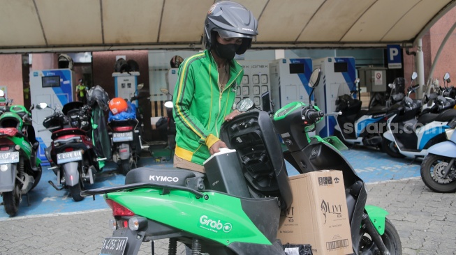 Pemilik kendaraan melakukan pengisian daya kendaraan listrik di SKPLU, Jakarta, Senin (7/7/2025). [Suara.com/Alfian Winanto]