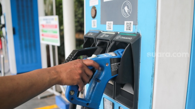 Pemilik kendaraan melakukan pengisian daya kendaraan listrik di SKPLU, Jakarta, Senin (7/7/2025). [Suara.com/Alfian Winanto]