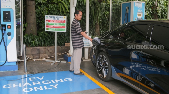 Pemilik kendaraan melakukan pengisian daya kendaraan listrik di SKPLU, Jakarta, Senin (7/7/2025). [Suara.com/Alfian Winanto]