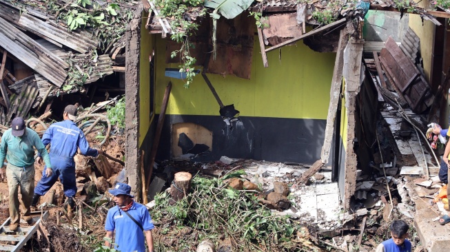 Petugas membersihkan material tanah longsor yang menimpa rumah di Megamendung, Puncak, Kabupaten Bogor, Jawa Barat, Senin (7/7/2025). [ANTARA FOTO/Yulius Satria Wijaya/nym]