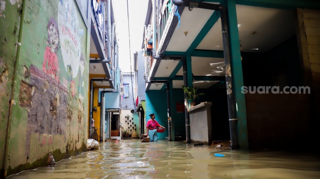 Warga beraktivitas di tengah banjir yang melanda pemukiman padat penduduk di kawasan Kebon Pala, Kampung Melayu, Jakarta, Selasa (8/7/2025). [Suara.com/Alfian Winanto]
