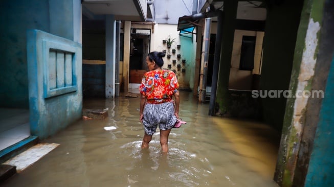 Warga beraktivitas di tengah banjir yang melanda pemukiman padat penduduk di kawasan Kebon Pala, Kampung Melayu, Jakarta, Selasa (8/7/2025). [Suara.com/Alfian Winanto]
