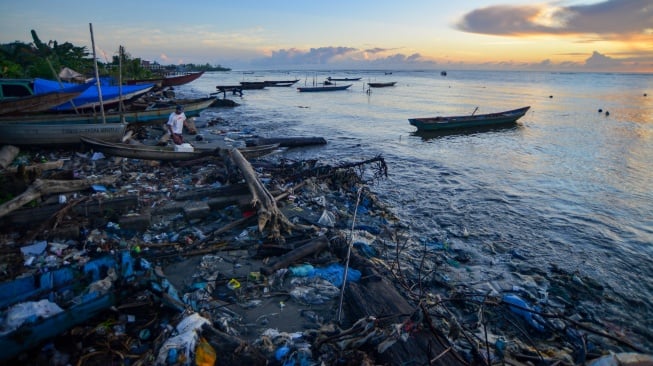 Nelayan mengeluarkan sampannya di antara sampah saat matahari terbit di Pantai Muara Siberut, Mentawai, Sumatera Barat, Selasa (8/7/2025). [ANTARA FOTO/Iggoy el Fitra/tom]