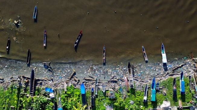 Foto udara sejumlah sampan berada di antara sampah di Pantai Muara Siberut, Mentawai, Sumatera Barat, Selasa (8/7/2025). [ANTARA FOTO/Iggoy el Fitra/tom]