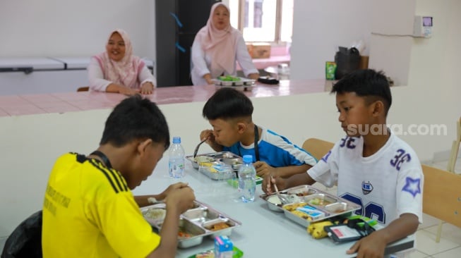 Siswa Makan Bergizi Gratis (MBG) pada pembukaan masa pengenalan lingkungan sekolah (MPLS) di Sekolah Rakyat Menengah Pertama (SRMP) Sentra Handayani, Jakarta, Senin (14/7/2025). [Suara.com/Alfian Winanto]