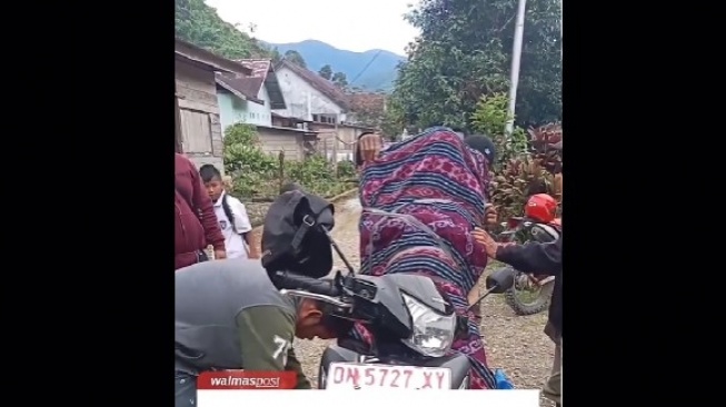Jenazah Ariel Sharon, Pegawai BKKBN Kecamatan Pinembani Kabupaten Donggala dibawa menggunakan sepeda motor oleh warga ke rumah duka di Kota Palu, Sulteng [Suara.com/Istimewa]