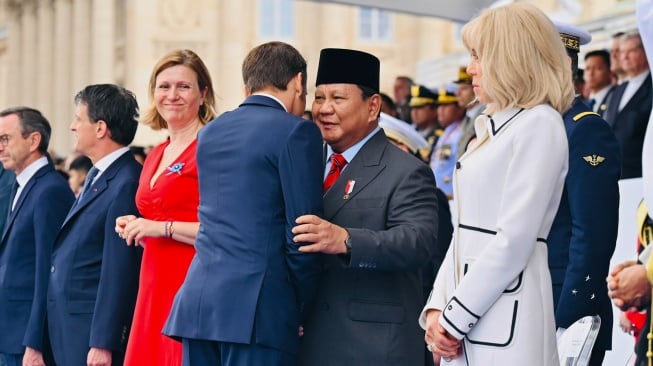 Presiden Prabowo Subianto (kedua kanan) berjabat tangan dengan Presiden Prancis Emmanuel Macron (ketiga kanan) disaksikan istri Brigitte Macron (kanan) saat meghadiri parade Bastille Day di jalan Champs-Elysees, Paris, Prancis, Senin (14/7/2025). [HO/Setpres-Laily Rachev]
