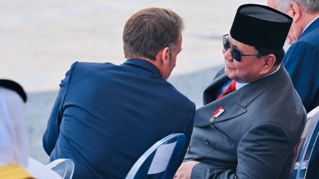 Presiden Prabowo Subianto (kanan) berjabat tangan dengan Presiden Prancis Emmanuel Macron (kiri) saat meghadiri parade Bastille Day di jalan Champs-Elysees, Paris, Prancis, Senin (14/7/2025). [HO/Setpres-Laily Rachev]
