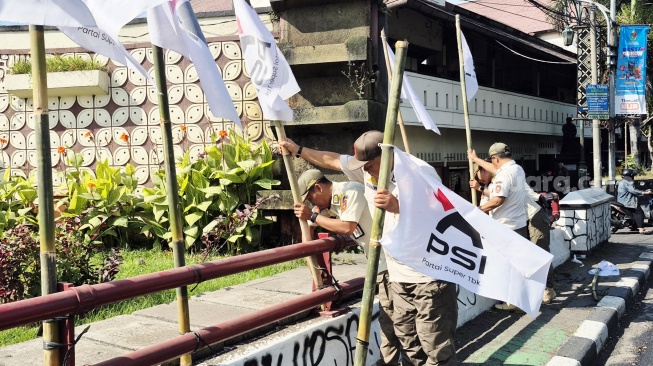 Petugas Satpol PP Solo saat menertibkan atribut PSI yang dipasang di zona larangan. (Suara.com/Ari Welianto)
