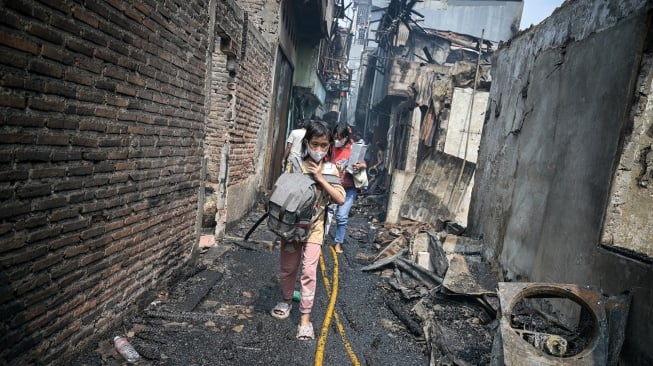 Warga berjalan membawa barangnya di tengah lokasi kebakaran permukiman penduduk di Duri Utara, Tambora, Jakarta, Senin (21/7/2025). [ANTARA FOTO/Fauzan/bar]