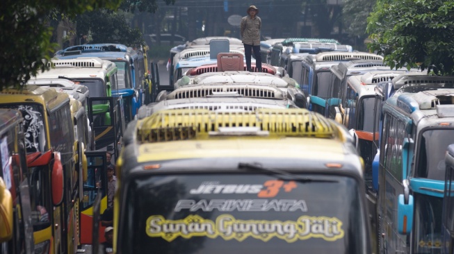 Demonstran yang tergabung dalam Solidaritas Pekerja Pariwisata Jawa Barat berdiri di atas bus saat aksi unjuk rasa di depan Gedung Sate, Bandung, Jawa Barat, Senin (21/7/2025). [ANTARA FOTO/Novrian Arbi/bar]
