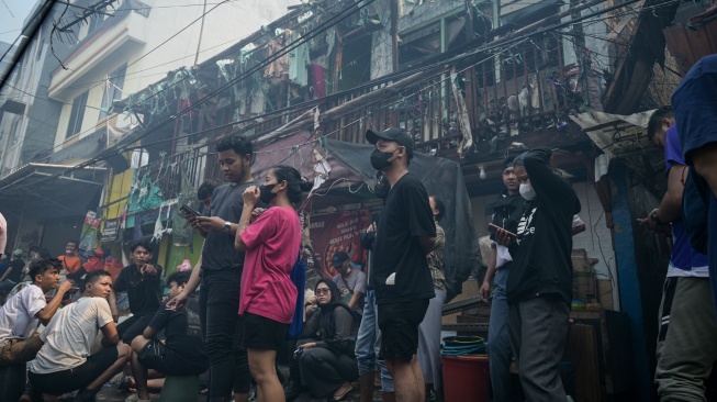 Sejumlah warga menyaksikan proses pendinginan di lokasi kebakaran permukiman penduduk di Duri Utara, Tambora, Jakarta, Senin (21/7/2025). [Suara.com/Alfian Winanto]
