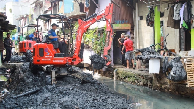 Petugas dari Suku Dinas Sumber Daya Air (SDA) Jakarta Pusat melakukan pengerukan lumpur di aliran anak Kali Krukut, Kebon Melati, Tanah Abang, Jakarta, Selasa (22/7/2025). [Suara.com/Alfian Winanto]
