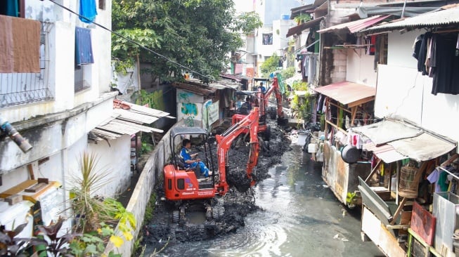 Petugas dari Suku Dinas Sumber Daya Air (SDA) Jakarta Pusat melakukan pengerukan lumpur di aliran anak Kali Krukut, Kebon Melati, Tanah Abang, Jakarta, Selasa (22/7/2025). [Suara.com/Alfian Winanto]