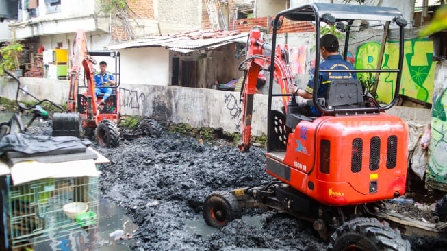 Petugas dari Suku Dinas Sumber Daya Air (SDA) Jakarta Pusat melakukan pengerukan lumpur di aliran anak Kali Krukut, Kebon Melati, Tanah Abang, Jakarta, Selasa (22/7/2025). [Suara.com/Alfian Winanto]