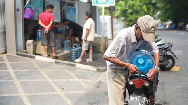 Warga mengisi air minum gratis di kawasan Rawamangun, Jakarta, Kamis (24/7/2025). [Suara.com/Alfian Winanto]
