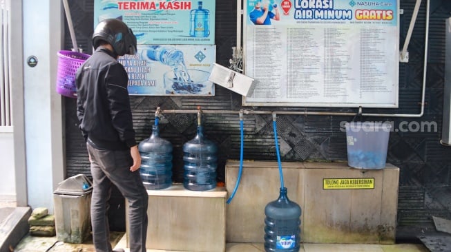 Warga mengisi air minum gratis di kawasan Rawamangun, Jakarta, Kamis (24/7/2025). [Suara.com/Alfian Winanto]
