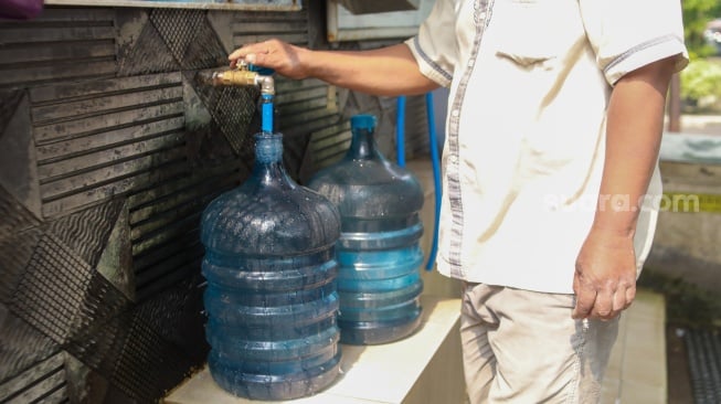 Warga mengisi air minum gratis di kawasan Rawamangun, Jakarta, Kamis (24/7/2025). [Suara.com/Alfian Winanto]
