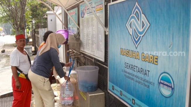 Warga mengisi air minum gratis di kawasan Rawamangun, Jakarta, Kamis (24/7/2025). [Suara.com/Alfian Winanto]

