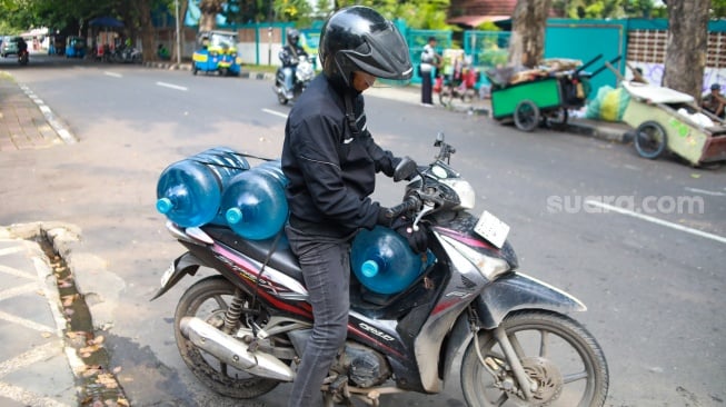 Warga mengisi air minum gratis di kawasan Rawamangun, Jakarta, Kamis (24/7/2025). [Suara.com/Alfian Winanto]
