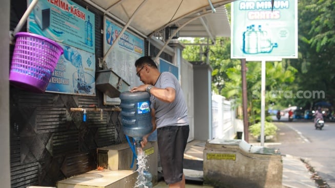 Warga mengisi air minum gratis di kawasan Rawamangun, Jakarta, Kamis (24/7/2025). [Suara.com/Alfian Winanto]
