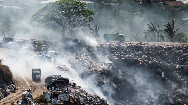 Pemulung memilah sampah di antara kepulan asap pembakaran sampah di tempat pembuangan akhir (TPA) ilegal, Rowosari, Tembalang, Jawa Tengah, Selasa (29/7/2025). [ANTARA FOTO/Aprillio Akbar/tom]