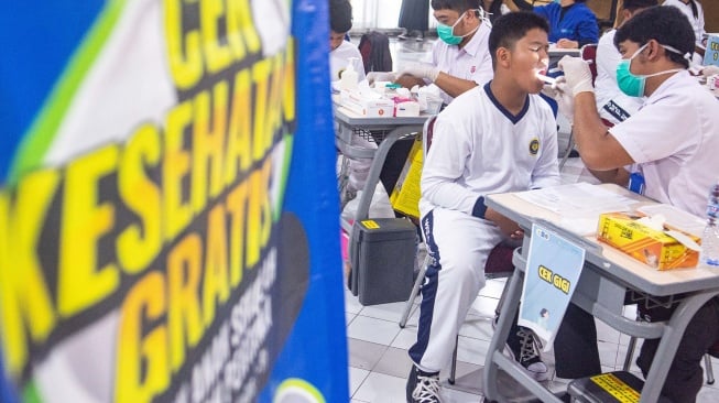 Petugas tenaga medis melakukan pemeriksaan kesehatan gratis kepada pelajar di SMPN 5, Bandung, Jawa Barat, Senin (4/8/2025). [ANTARA FOTO/Novrian Arbi/YU]
