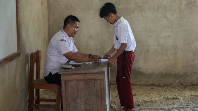 Seorang siswa kelas lima mengumpulkan tugas kepada gurunya di SD Negeri 1 Curug, Kecamatan Cibaliung, Pandeglang, Banten, Rabu (6/8/2025). [ANTARA FOTO/Muhammad Bagus Khoirunas/foc]