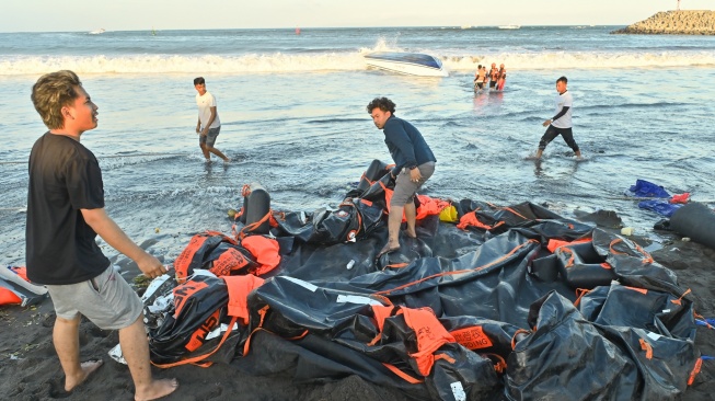 Warga berusaha menarik barang-barang dari kapal cepat Bali Dolphin Cruise 2 yang mengalami kecelakaan ke tepi pantai di kawasan Sanur, Denpasar, Bali, Selasa (5/8/2025). [ANTARA FOTO/Fikri Yusuf/YU]