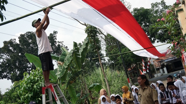 Sejumlah warga bergotong royong memasang bendera merah putih di atas jalan desa di Dukuh Rejosari, Desa Kayugeritan, Kecamatan Karanganyar, Kabupaten Pekalongan, Jawa Tengah, Selasa (5/8/2025). [ANTARA FOTO/Harviyan Perdana Putra/bar]