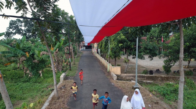 Warga melintasi bendera merah putih yang terbentang di atas jalan desa di Dukuh Rejosari, Desa Kayugeritan, Kecamatan Karanganyar, Kabupaten Pekalongan, Jawa Tengah, Selasa (5/8/2025). [ANTARA FOTO/Harviyan Perdana Putra/bar]