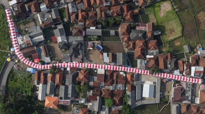 Foto udara kain merah putih terpasang di jalan Kampung Cibahong, Desa Sukamenak, Kecamatan Sukarame, Kabupaten Tasikmalaya, Jawa Barat, Rabu (6/8/2025). [ANTARA FOTO/Adeng Bustomi/tom]