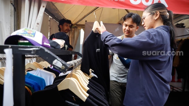 Pembeli memillih busana yang dijual dalam pameran JakCloth Summerfest 2025 di Blok M Hub, Jakarta, Sabtu (9/8/2025). [Suara.com/Alfian Winanto]