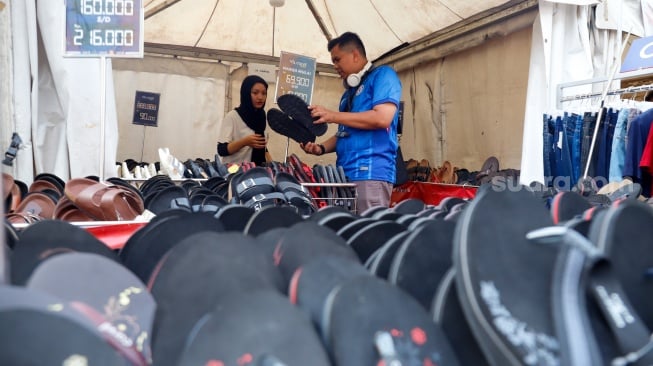 Pembeli memillih sandal yang dijual dalam pameran JakCloth Summerfest 2025 di Blok M Hub, Jakarta, Sabtu (9/8/2025). [Suara.com/Alfian Winanto]
