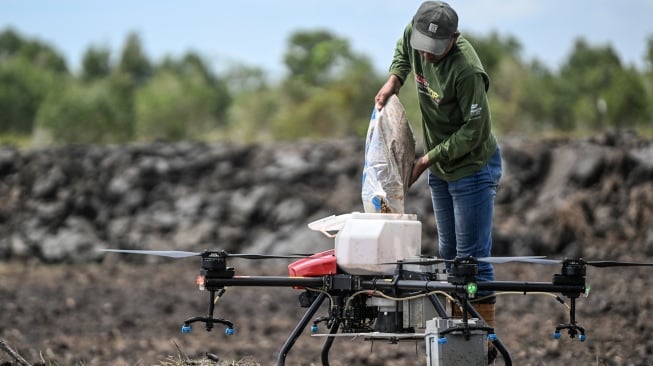 Pekerja menuangkan benih padi di drone untuk ditebar saat tanam perdana di lokasi cetak sawah rakyat (CSR) di kawasan Bati-Bati, Tanah Laut, Kalimantan Selatan, Selasa (12/8/2025). [ANTARA FOTO/Hafidz Mubarak A/YU]
