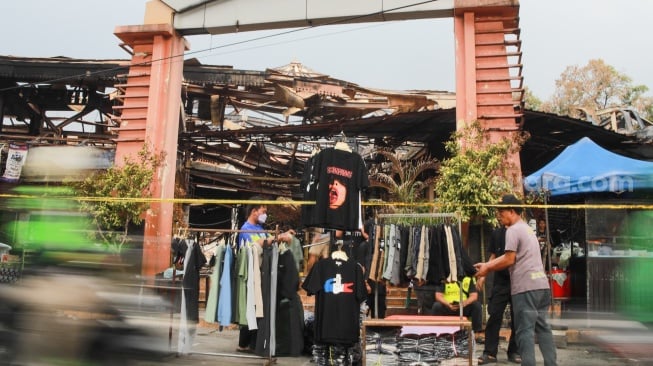 Pedagang menjajakan dagangannya pada lokasi bekas kebakaran di Pasar Taman Puring, Jakarta, Rabu (13/8/2025). [Suara.com/Alfian Winanto]