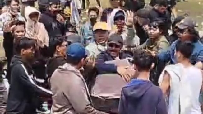 Tangkapan layar seorang warga menghalau massa lain mengeroyok polisi saat demo Pati di Alun-alun Pati. (X.com)