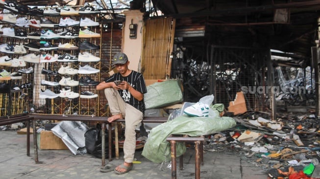 Pedagang menjajakan dagangannya pada lokasi bekas kebakaran di Pasar Taman Puring, Jakarta, Rabu (13/8/2025). [Suara.com/Alfian Winanto]