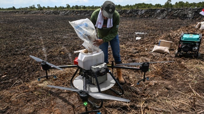 Pekerja menuangkan benih padi di drone untuk ditebar saat tanam perdana di lokasi cetak sawah rakyat (CSR) di kawasan Bati-Bati, Tanah Laut, Kalimantan Selatan, Selasa (12/8/2025). [ANTARA FOTO/Hafidz Mubarak A/YU]