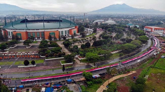 Foto udara peserta membentangkan Bendera Merah Putih dalam Kirab Merah Putih di Lingkar Stadion Pakansari, Kabupaten Bogor, Jawa Barat, Kamis (14/8/2025). [ANTARA FOTO/Yulius Satria Wijaya/nym]