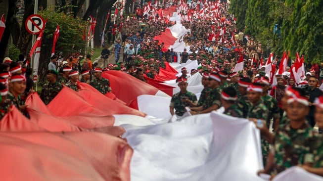 Sejumlah personel TNI dan Polri membentangkan Bendera Merah Putih dalam Kirab Merah Putih di Lingkar Stadion Pakansari, Kabupaten Bogor, Jawa Barat, Kamis (14/8/2025). [ANTARA FOTO/Yulius Satria Wijaya/nym]

