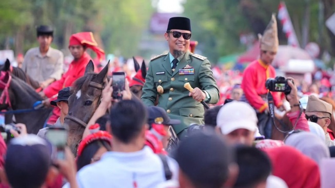 Gubernur Sulawesi Selatan, Andi Sudirman Sulaiman memakai kostum menyerupai kostum Bung Karno, melepas ribuan peserta jalan sehat dan kirab karnaval, Sabtu (16/8/2025) [Suara.com/Humas Pemprov Sulsel]