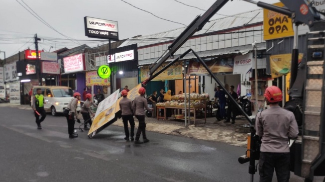 Sejumlah anggota polisi ikut mengevakuasi baliho roboh dampak kerusakan akibat hujan deras dan angin kencang di Sleman pada Selasa (19/8/2025). (dok.Istimewa)