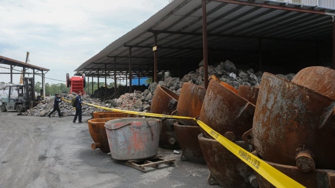 Petugas Penegakan Hukum (Gakkum) Kementerian Lingkungan Hidup memasang tanda garis larangan melintas dan plang penyegelan di area pabrik PT Genesis Regeneration Smelting, Jawilan, Kabupaten Serang, Banten, Kamis (21/8/2025). [Suara.com/Alfian Winanto]