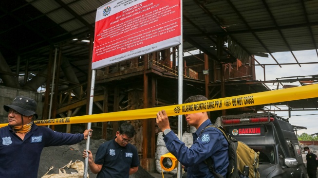Petugas Penegakan Hukum (Gakkum) Kementerian Lingkungan Hidup memasang tanda garis larangan melintas dan plang penyegelan di area pabrik PT Genesis Regeneration Smelting, Jawilan, Kabupaten Serang, Banten, Kamis (21/8/2025). [Suara.com/Alfian Winanto]