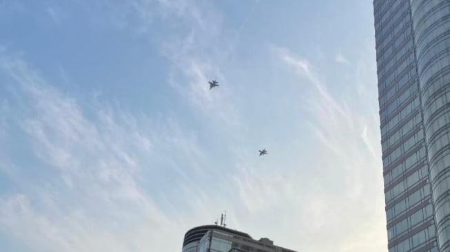 Dua Pesawat Tempur milik TNI AU melakukan manuver di jantung Kota Jakarta pada ajang balap lari Merdeka Run 8.0 K dalam rangka puncak perayaan HUT ke-80 Republik Indonesia, Minggu (24/8/2025). [Suara.com/Novian]