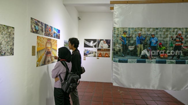 Pengunjung melihat foto yang dipamerkan pada pameran foto Rekam Jakarta 2025 di Cemara 6 Galeri, Jakarta, Sabtu (23/8/2025). [Suara.com/Alfian Winanto]